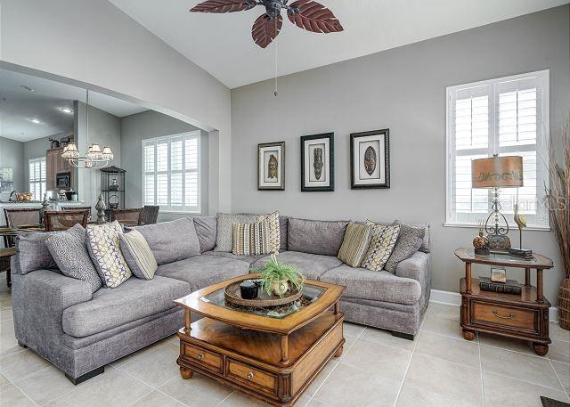 tiled living room featuring ceiling fan with notable chandelier and lofted ceiling