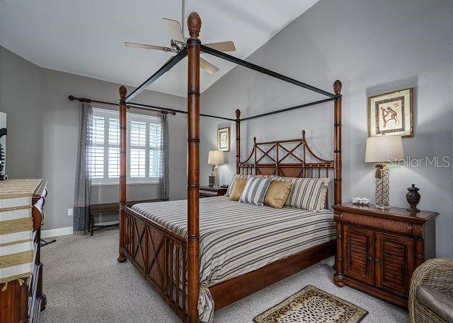 bedroom with ceiling fan, light carpet, and vaulted ceiling