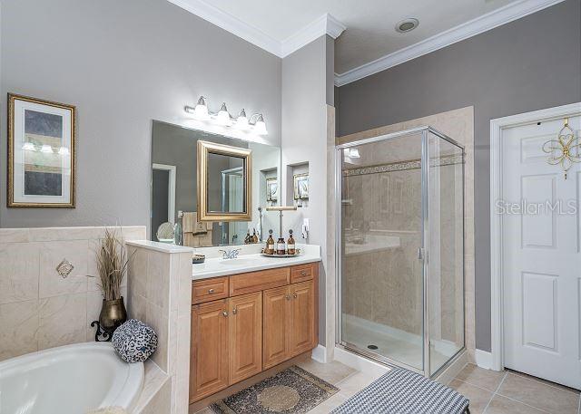 bathroom featuring vanity, tile patterned flooring, plus walk in shower, and ornamental molding