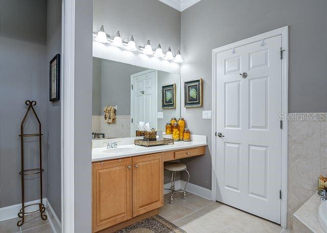 bathroom featuring tile patterned floors, vanity, and a relaxing tiled tub