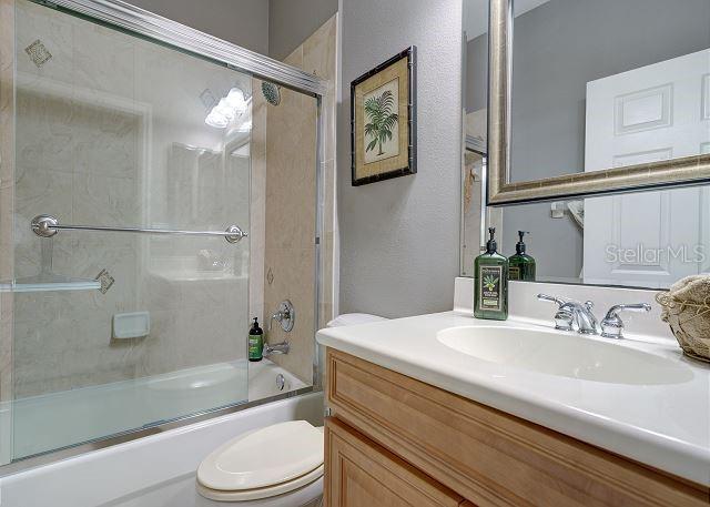 full bathroom with vanity, toilet, and enclosed tub / shower combo