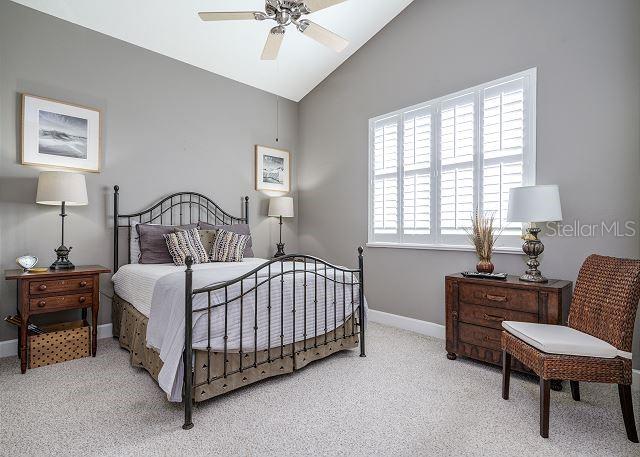 carpeted bedroom featuring ceiling fan and vaulted ceiling