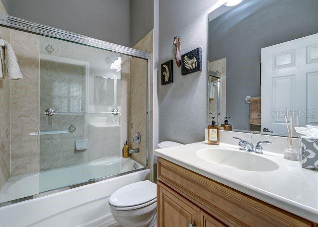 full bathroom featuring shower / bath combination with glass door, vanity, and toilet