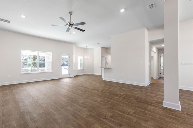 unfurnished living room with dark wood-type flooring and ceiling fan with notable chandelier