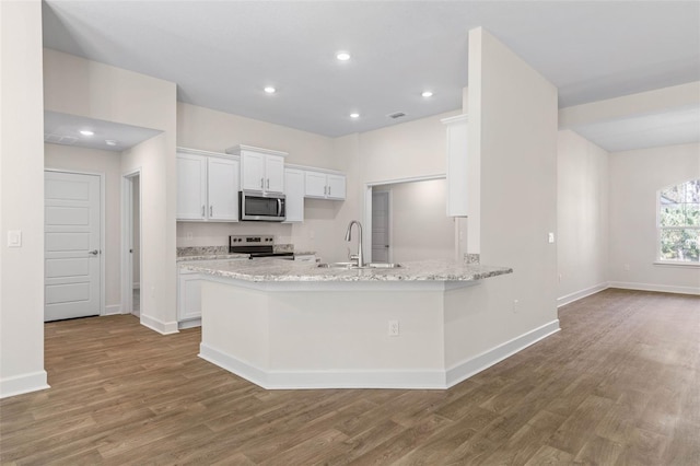 kitchen featuring wood-type flooring, white cabinetry, appliances with stainless steel finishes, and kitchen peninsula