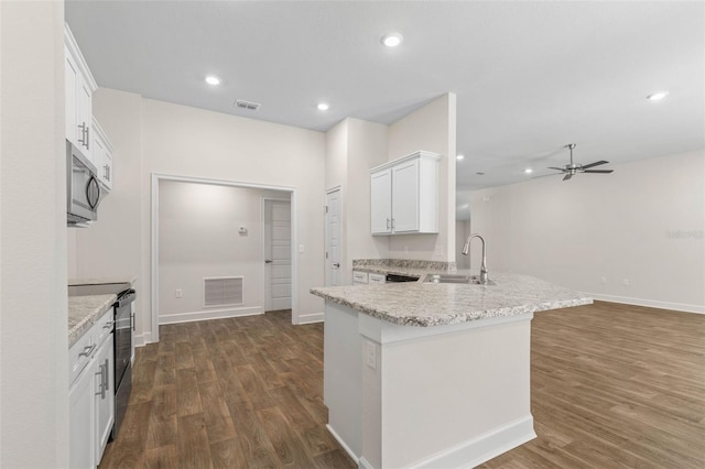 kitchen with electric range oven, sink, white cabinets, dark hardwood / wood-style flooring, and light stone counters