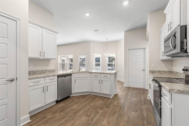 kitchen featuring kitchen peninsula, pendant lighting, stainless steel appliances, and white cabinetry