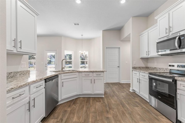 kitchen featuring sink, white cabinetry, hanging light fixtures, dark wood-type flooring, and stainless steel appliances