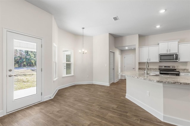 kitchen with appliances with stainless steel finishes, decorative light fixtures, white cabinets, light stone counters, and sink