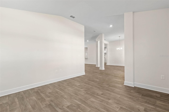 empty room featuring a chandelier, lofted ceiling, and hardwood / wood-style floors