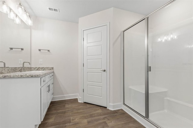 bathroom with hardwood / wood-style flooring, walk in shower, and vanity