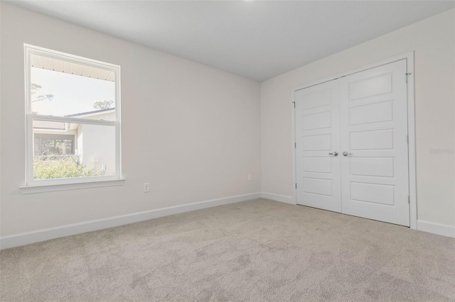 unfurnished bedroom featuring light carpet and a closet