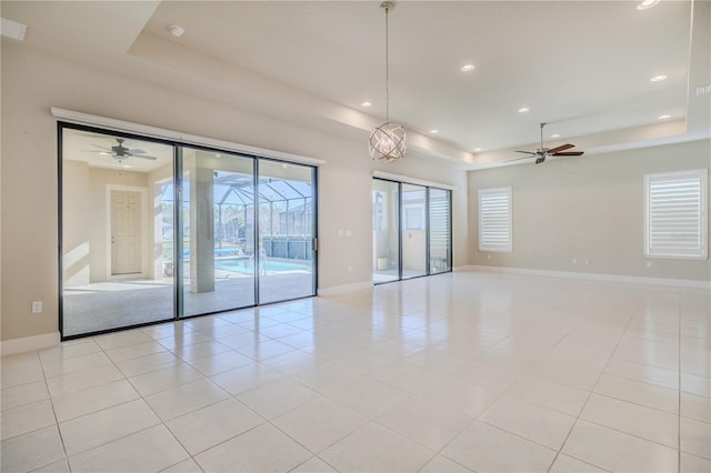 unfurnished room with a raised ceiling, ceiling fan, and light tile patterned flooring