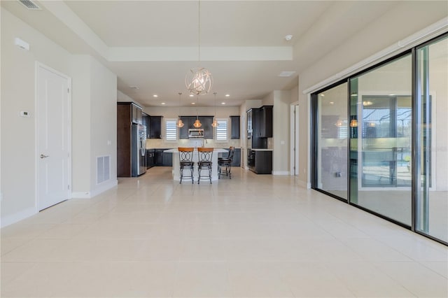 kitchen featuring a kitchen bar, stainless steel fridge, an inviting chandelier, a kitchen island, and hanging light fixtures