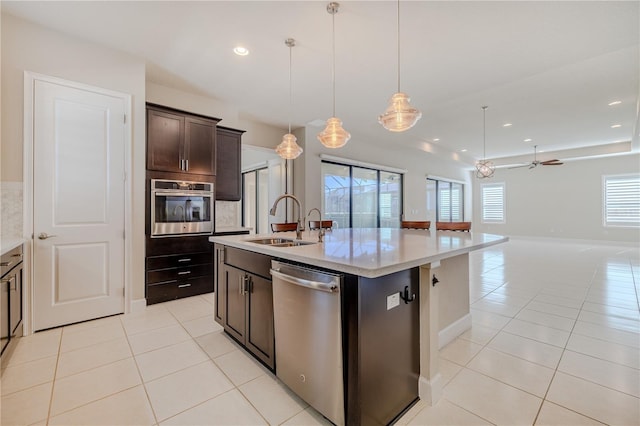 kitchen featuring ceiling fan, sink, stainless steel appliances, a center island with sink, and light tile patterned floors