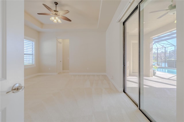 carpeted empty room featuring a tray ceiling and ceiling fan