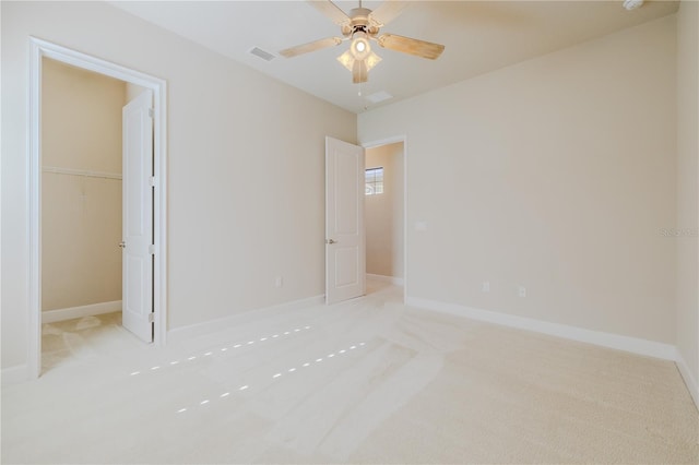 unfurnished bedroom featuring ceiling fan, a walk in closet, light carpet, and a closet