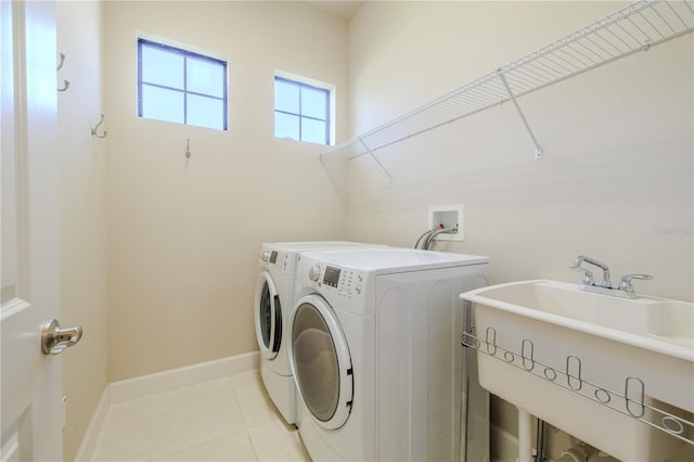 washroom with washing machine and dryer, sink, and light tile patterned flooring