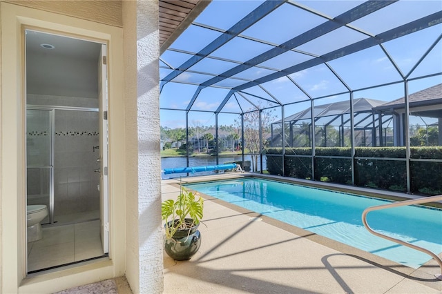 view of pool with glass enclosure and a patio