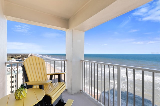 balcony with a water view and a view of the beach