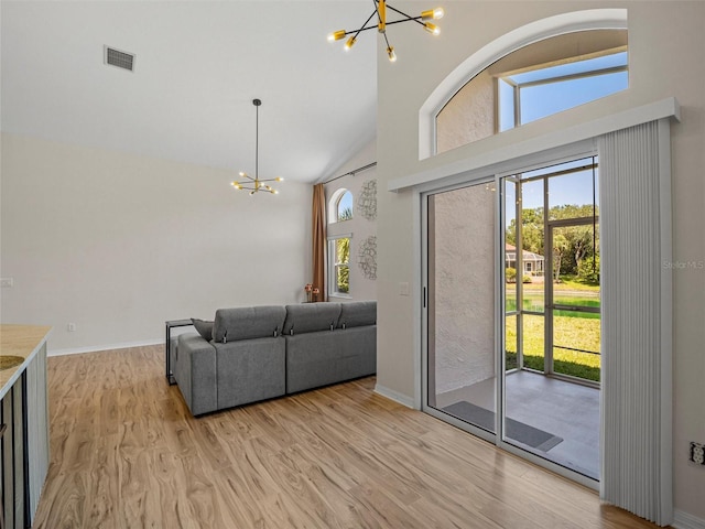 living room featuring a notable chandelier, high vaulted ceiling, and light hardwood / wood-style flooring