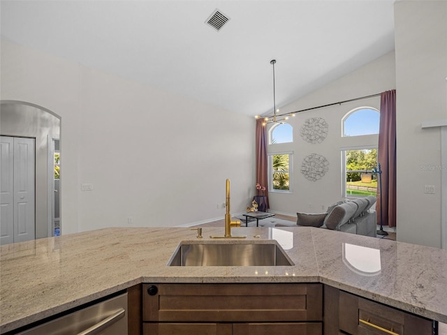 kitchen with dishwasher, sink, light stone counters, and vaulted ceiling