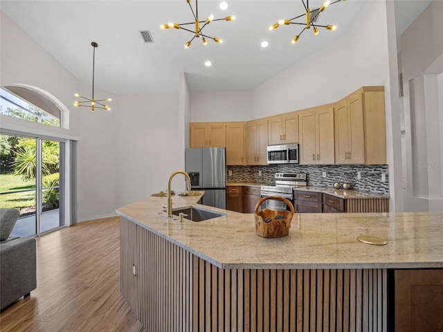 kitchen featuring sink, stainless steel appliances, light stone counters, high vaulted ceiling, and light wood-type flooring