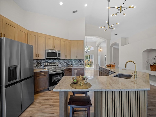 kitchen with sink, hanging light fixtures, a large island, light hardwood / wood-style floors, and stainless steel appliances