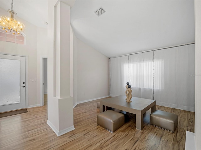 dining area with a chandelier, high vaulted ceiling, light hardwood / wood-style flooring, and a healthy amount of sunlight