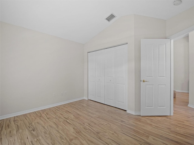 unfurnished bedroom with a closet, lofted ceiling, and light wood-type flooring