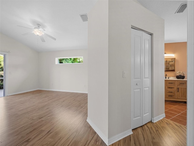 empty room featuring plenty of natural light, light hardwood / wood-style floors, ceiling fan, and vaulted ceiling