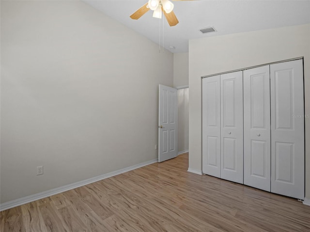 unfurnished bedroom with ceiling fan, a closet, light hardwood / wood-style floors, and vaulted ceiling