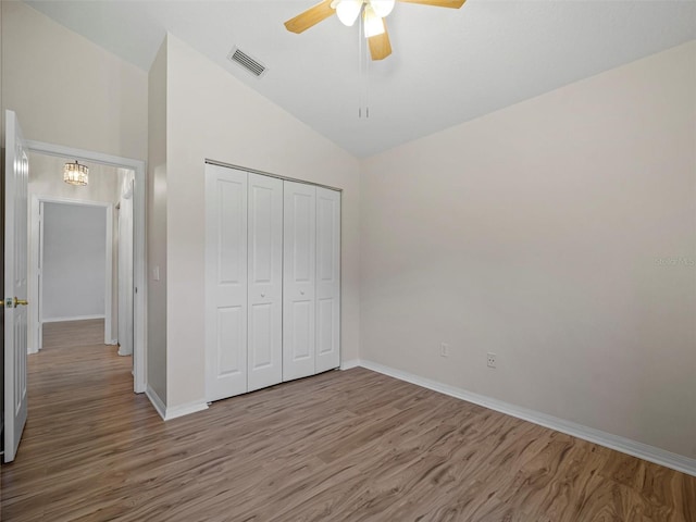 unfurnished bedroom featuring ceiling fan, wood-type flooring, high vaulted ceiling, and a closet