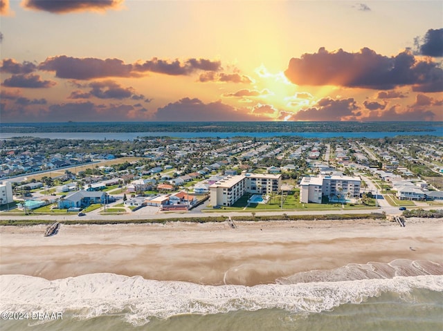 aerial view at dusk with a view of the beach and a water view