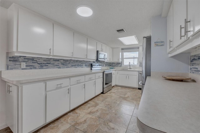 kitchen featuring backsplash, white cabinets, sink, a textured ceiling, and stainless steel appliances