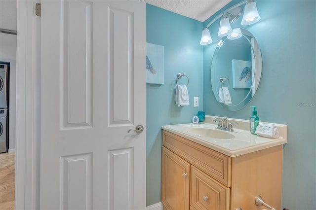 bathroom featuring vanity, a textured ceiling, and stacked washer / dryer