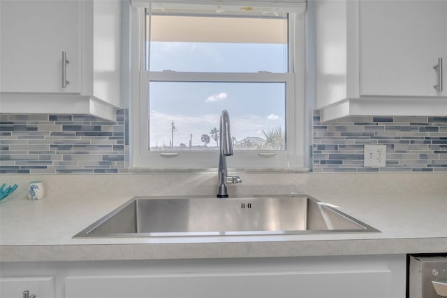 kitchen with tasteful backsplash, sink, and white cabinets