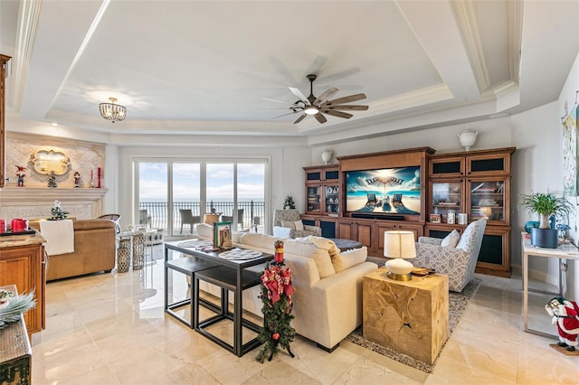 living room with a raised ceiling, ceiling fan, and ornamental molding