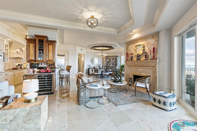 living room with a fireplace, crown molding, beverage cooler, and a notable chandelier