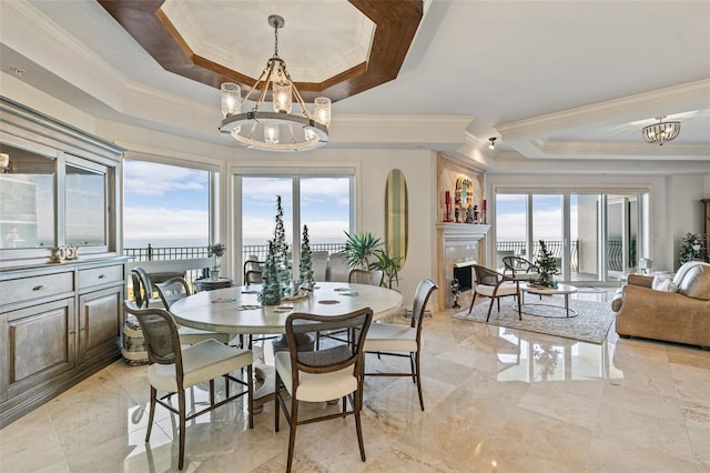 dining area featuring a raised ceiling, a high end fireplace, ornamental molding, and an inviting chandelier