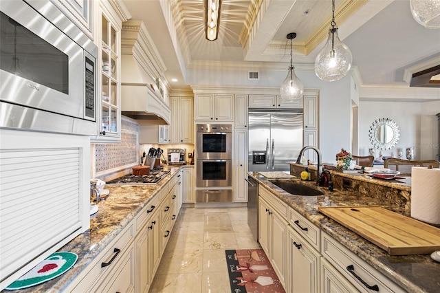 kitchen with dark stone counters, cream cabinetry, hanging light fixtures, and appliances with stainless steel finishes