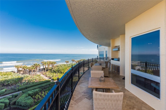 balcony featuring a view of the beach and a water view