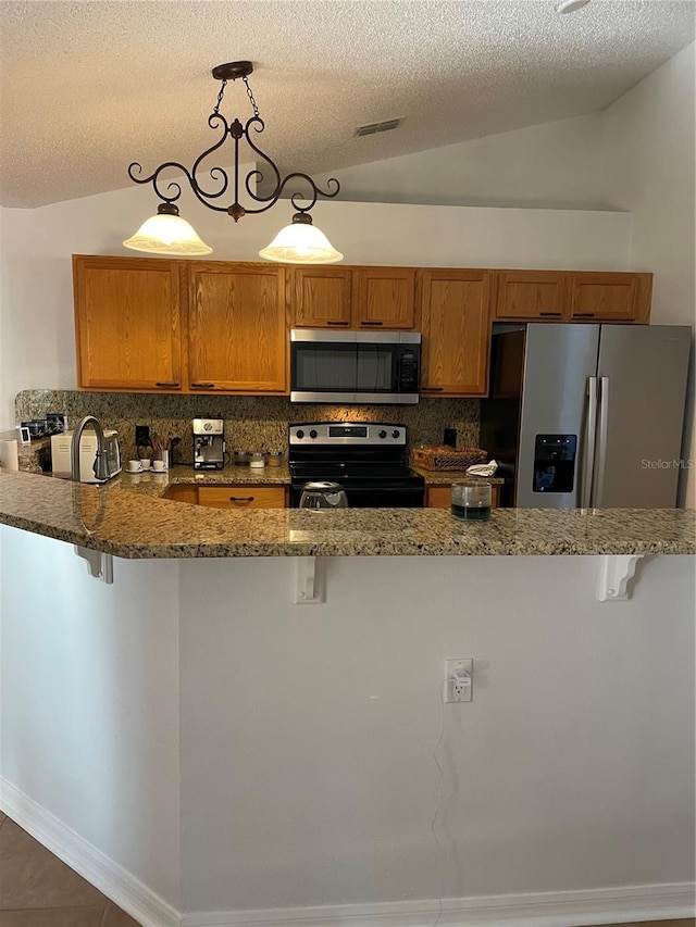 kitchen featuring a kitchen bar, lofted ceiling, brown cabinetry, and appliances with stainless steel finishes