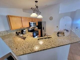 kitchen with light stone countertops, decorative light fixtures, a peninsula, stainless steel appliances, and a sink