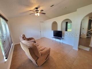 living room featuring visible vents, lofted ceiling, arched walkways, and ceiling fan