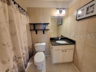 bathroom with vanity, tile walls, toilet, and tile patterned floors