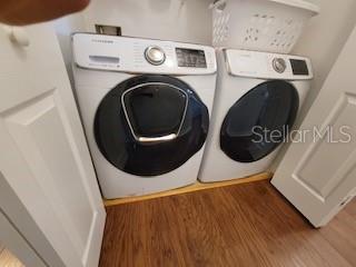 laundry area with laundry area, washer and dryer, and wood finished floors