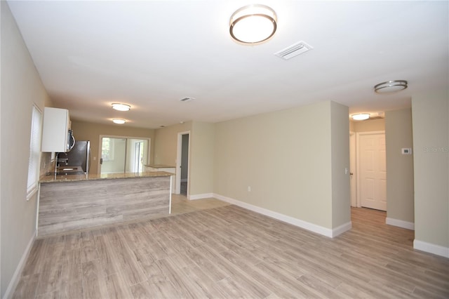 unfurnished living room featuring sink and light wood-type flooring