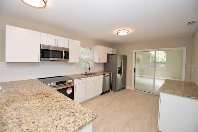 kitchen featuring white cabinetry, stainless steel appliances, sink, tasteful backsplash, and a healthy amount of sunlight