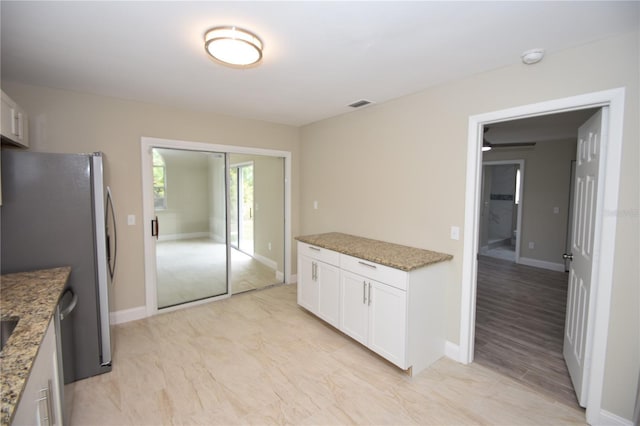 kitchen with white cabinetry, stone counters, and stainless steel fridge